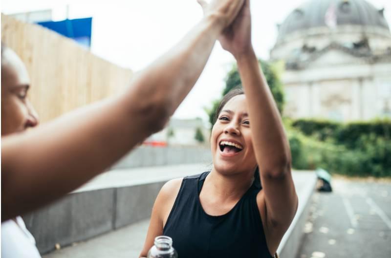 Two women giving a high five outside